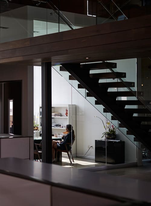 Modern office interior with glass walls and staircase, highlighting construction services for workspace design.