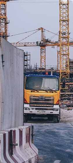 Yellow construction truck and cranes at an active worksite, illustrating construction services in progress.