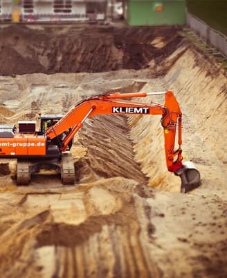 Excavator digging at a large construction site, demonstrating earthmoving construction services.